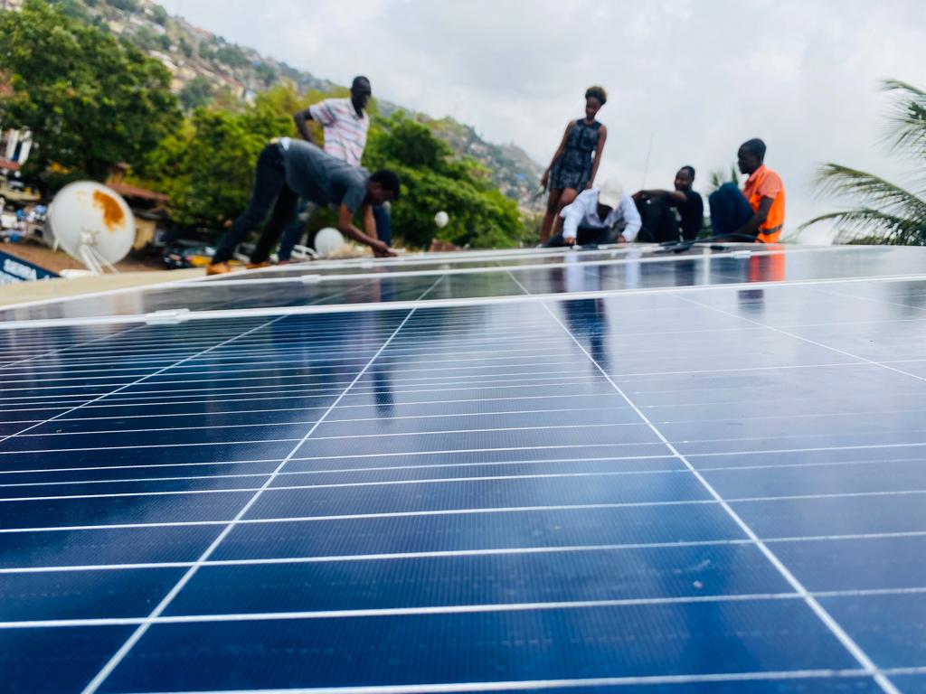 Image of a young people in Sierra Leone working on installing a solar panel.
